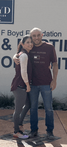 a man wearing a tommy hilfiger shirt stands with a woman