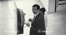 a black and white photo of a man using an atm