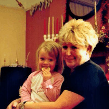 a woman is holding a little girl in her arms while the little girl is eating a cookie .