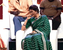 a woman in a green and white striped saree sits in a chair with the word venkat on the bottom