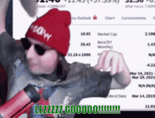 a man wearing a red beanie and sunglasses stands in front of a microphone and says lezzzz goooo