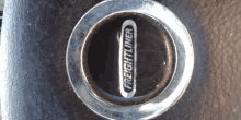 a close up of a freightliner wheel cap on a black surface