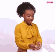 a girl in a yellow shirt is playing a game of cards with a stack of cards in front of her .