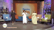 a woman in a white dress stands in front of a stage that says magandang buhay