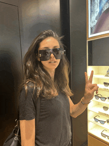 a woman wearing sunglasses is giving a peace sign in front of a display of dior sunglasses