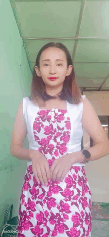 a woman wearing a pink and white floral dress is standing in a room .