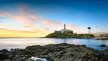 a lighthouse sits on a rocky cliff overlooking the ocean