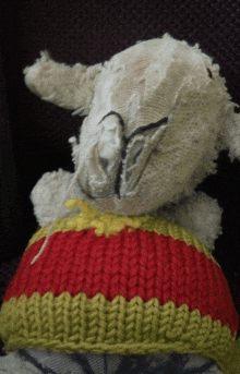 a stuffed animal wearing a red and yellow striped hat