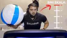 a man wearing a shirt that says bmi666 holds a beach ball