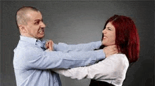 a man and a woman are fighting with each other . the woman is holding the man 's neck .