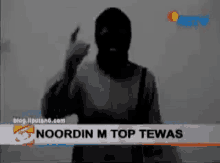 a man in a mask is standing in front of a banner that says noordin m top tewas on it