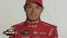 a man is wearing a red racing suit with a monster energy logo on it