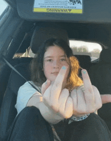 a girl giving the middle finger in a car with a warning on the visor