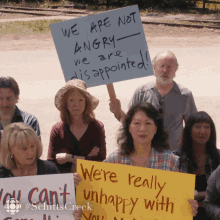 a group of people holding up signs including one that says " we are not angry we are disappointed "