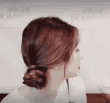 a woman is wearing a white shirt and a braided bun .