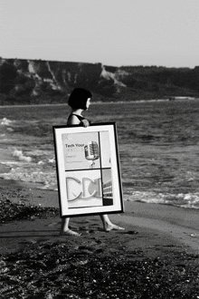 a black and white photo of a woman holding a framed poster that says tech your life