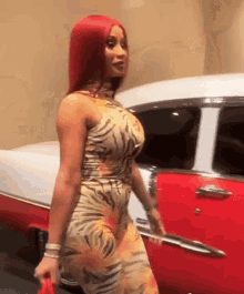 a woman with red hair is standing next to a red car .