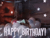 a woman is laying in a pile of balloons with the words `` happy birthday '' written above her .