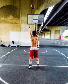 a man without a shirt is throwing a basketball into a hoop