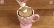 a pink cup with a heart on it is being decorated with frosting