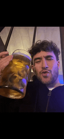 a man with a beard is holding a large glass of beer in his hand .