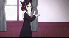 a girl in a black dress is pointing at something in a room