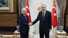 two men are shaking hands in front of flags with stars on them