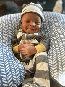 a baby wearing a striped outfit and hat is smiling