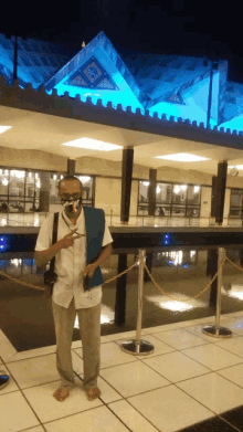 a man wearing a face mask stands in front of a building