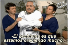 a man in a white shirt is being carried by two men in blue scrubs with the words el problema es que estamos creciendo mucho