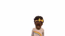 a little girl wearing a rainbow shirt with a yellow bow