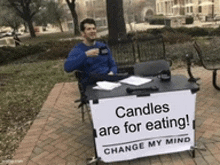 a man sitting at a desk with a sign that says candles are for eating