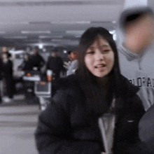 a woman in a black jacket is standing in front of a crowd of people in a parking garage .