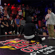 a group of people sitting in a stadium with a red bull logo on the floor in front of them