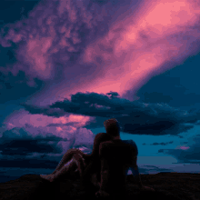 a man sits on a rock looking at the clouds