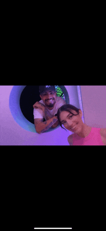 a man and a woman are posing for a picture in a room with a purple light behind them .