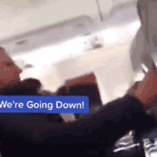 a man on an airplane with a sign that says " we 're going down "