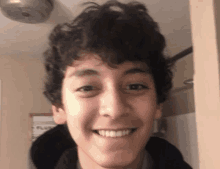 a young man with curly hair is smiling in front of a sign that says plumbing