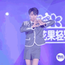 a person in a suit and shorts stands on a stage with chinese writing on the bottom