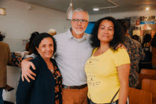 a man and two women are posing for a picture and one woman is wearing a yellow gucci shirt