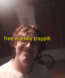 a man wearing glasses is smiling with the words free my boy trappik above him