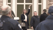 a woman is waving her hand in front of a police officer while standing in front of a house .