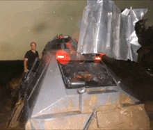 a man in a black shirt stands in front of a very large vehicle