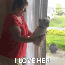 a woman in a red shirt is holding a small white dog with the words i love her below it