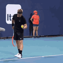 a man is holding a tennis ball and a racket on a tennis court with a sign that says it