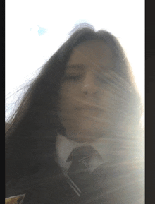 a girl in a school uniform is looking at the camera with the sun shining through her hair