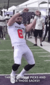 a football player is dancing on a field with his arms in the air while wearing a white jersey with the number 6 on it .