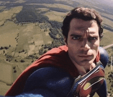 a man in a superman costume is flying over a field