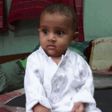 a baby wearing a white shirt is sitting on a couch