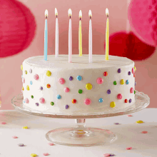 a birthday cake with colorful polka dots and lit candles